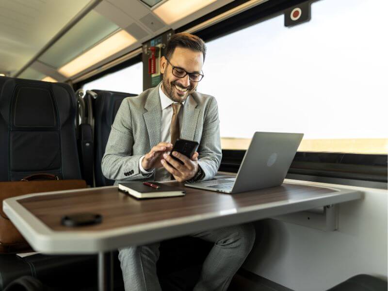 Man in a suit working on a laptop and phone while traveling