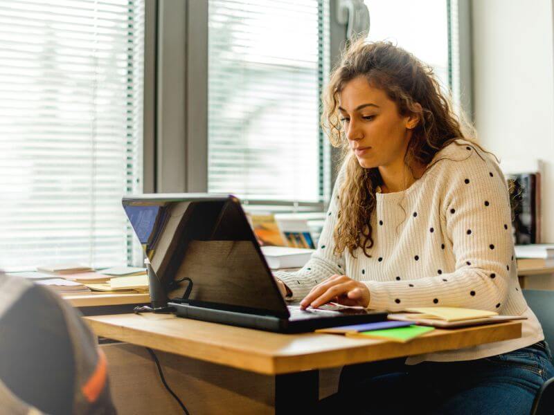 Student studying at a desk with a laptop and notebook